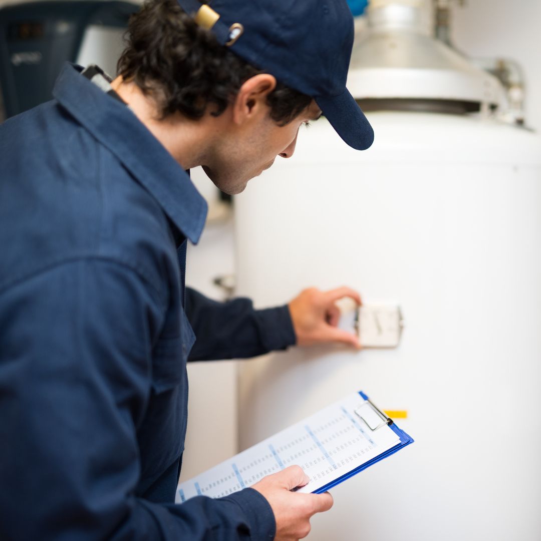 Water heater inspecting a water heater, holding a clipboard. 